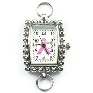May include: Silver-toned rectangular pocket watch with a white face featuring black numerals and a pink ribbon. The watch has a beaded border and two ring attachments. The watch face reads "GENEVA QUARTZ JAPAN MOVT".