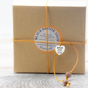 Puede incluir: Una caja de cart&oacute;n marr&oacute;n con una etiqueta que dice "Black Brook Shop" y una etiqueta en forma de coraz&oacute;n que dice "Made for You".