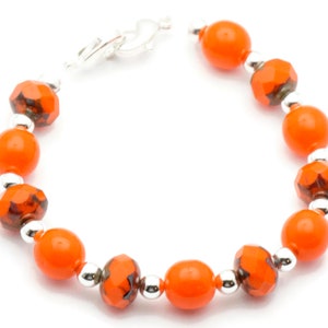 May include: Orange and silver beaded bracelet with a clasp closure.