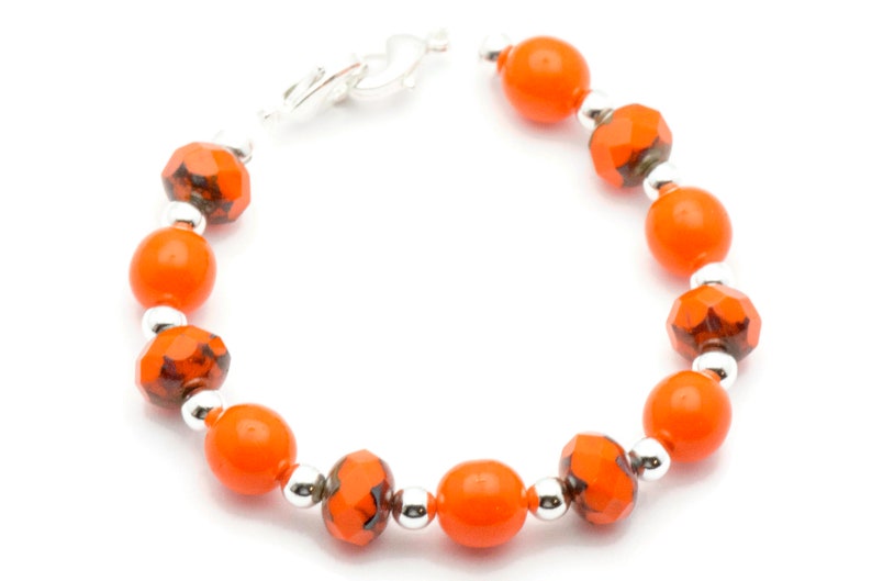 May include: Orange and silver beaded bracelet with a clasp closure.
