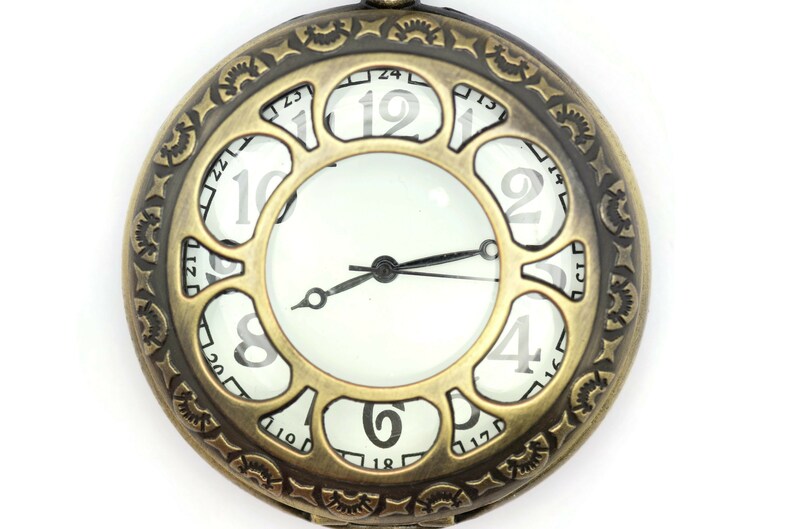 K&ouml;nnte beinhalten: Eine Taschenuhr im Vintage-Stil mit einem messingfarbenen Geh&auml;use und einem wei&szlig;en Zifferblatt. Die Uhr hat r&ouml;mische Ziffern als Stundenmarkierungen und ein skelettartiges Design, das das Innenleben der Uhr freilegt.