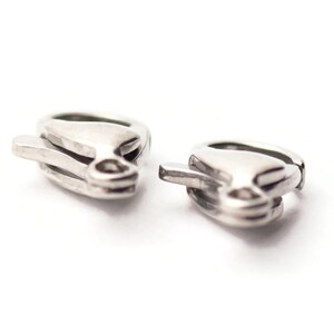 May include: Two silver-toned earring clasps, each with a curved, open design.