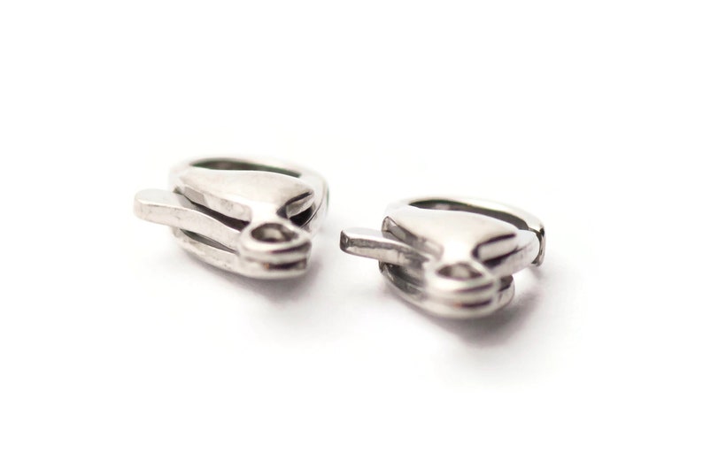 May include: Two silver-toned earring clasps, each with a curved, open design.