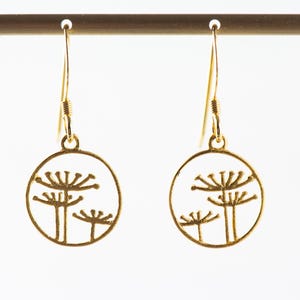 May include: Gold dangle earrings with a circular design featuring three stylized flower silhouettes.