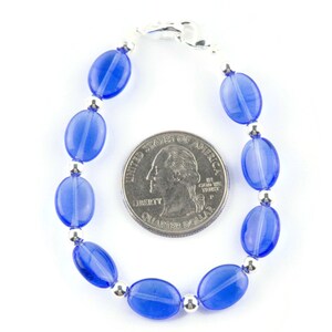 May include: A blue glass bead bracelet with silver accents. The bracelet is about the size of a quarter.