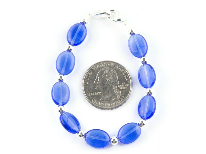 May include: A blue glass bead bracelet with silver accents. The bracelet is about the size of a quarter.