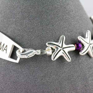 May include: Silver medical ID bracelet with a purple bead and star charm. The bracelet has the word "ASTHMA" engraved on the tag.