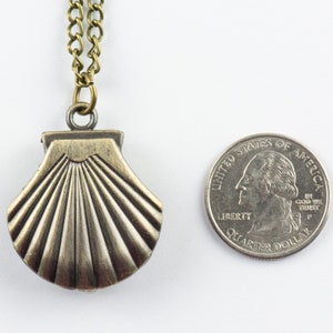 May include: A silver-toned seashell pendant necklace with a brass chain. The pendant is about the size of a UK 20 pence coin.