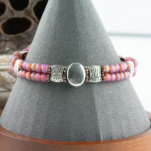 Button and Bows Raspberry Sorbet Cuff Memory Wire Bracelet on a decorative black bracelet stand