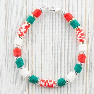 May include: A green, red, and white beaded bracelet with a silver clasp. The beads are stacked in a repeating pattern.