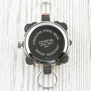 May include: Silver watch with a square face and a stainless steel back. The watch has a Geneva Japan Movt 2035-T movement and is water resistant.