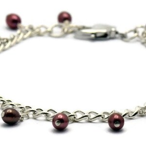 May include: A silver chain bracelet with a lobster clasp and multiple dangling maroon pearls.