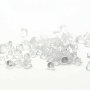 May include: A pile of clear plastic earring backs. The backs are small and round, with a small hole in the center. They are designed to be used with stud earrings.