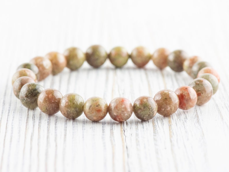 May include: A bracelet made of green, brown, and pink speckled stone beads.