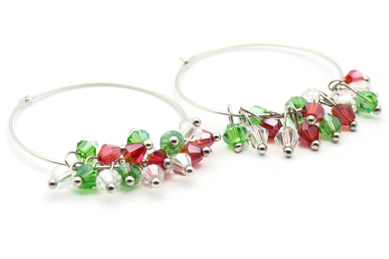 May include: Silver hoop earrings with red, green, and clear crystal beads dangling from the hoops.