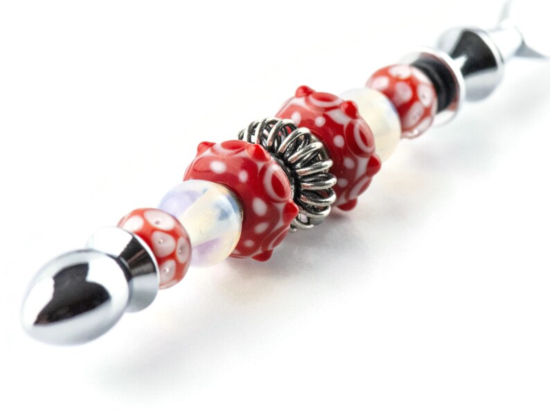 Peut inclure: Un bracelet &agrave; breloques argent&eacute; avec des perles de verre &agrave; motifs rouges et blancs et une perle d'espacement argent&eacute;e.