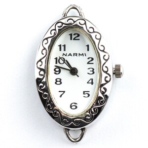 May include: Silver oval watch face with a white dial and black hands. The watch face has a decorative filigree border and the brand name "NARMI" is printed above the centre. The watch shows the time as 10:09.