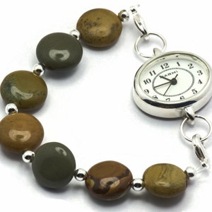 May include: A silver watch with a white face and black hands. The watch is attached to a bracelet made of brown and green stones.