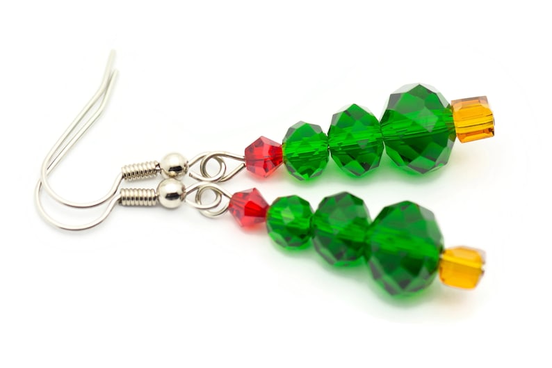 May include: A pair of silver dangle earrings with green and red crystal beads shaped like a Christmas tree. The earrings have a silver hook closure.