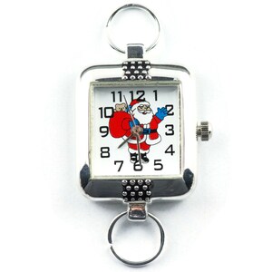 Pu&ograve; includere: Un orologio quadrato argentato con un quadrante bianco e un design di Babbo Natale. L'orologio ha un anello di perline nere attorno al bordo del quadrante e un portachiavi argentato.