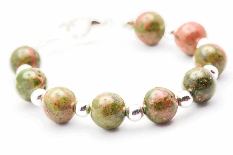May include: A bracelet made of green and pink speckled beads with silver spacers.