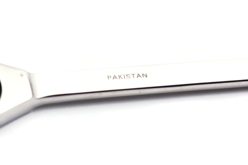 Puede incluir: Una llave inglesa plateada con la palabra "PAKISTAN" grabada en el mango.