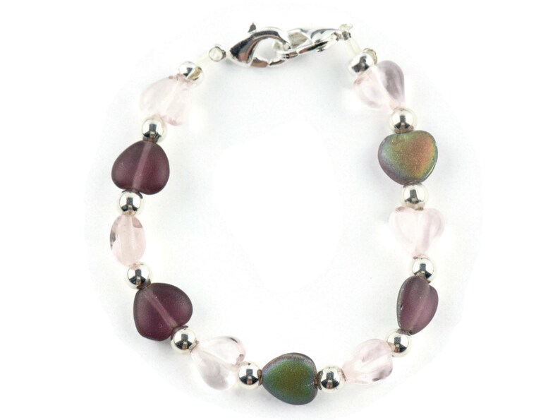 May include: A bracelet with silver beads and heart-shaped glass beads in shades of pink and purple.