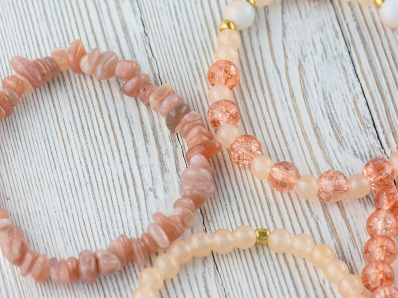 May include: Three bracelets made of natural stones. The first bracelet is made of light peach-coloured sunstone beads. The second bracelet is made of peach-coloured glass beads with gold flecks. The third bracelet is made of light peach-coloured glass beads with gold accents.