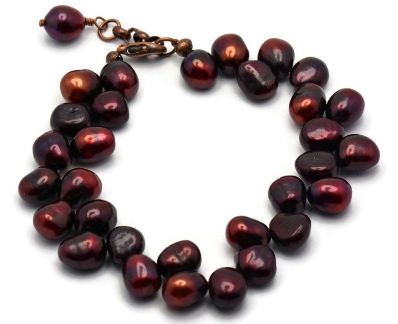 May include: A dark red freshwater pearl bracelet with a copper clasp. The pearls are irregular in shape and have a high luster.