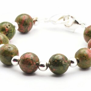 May include: A green and pink gemstone bracelet with silver beads and a silver clasp.