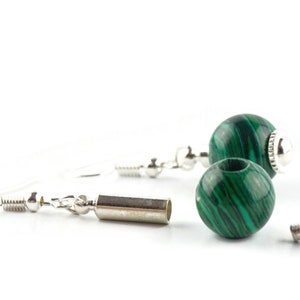 May include: A pair of earrings with green malachite stone beads and silver metal accents. The earrings are separated into their components, showing the beads, the silver ear wires, and the silver jump rings.