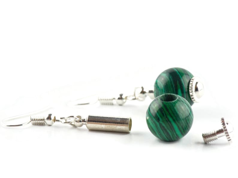 May include: A pair of earrings with green malachite stone beads and silver metal accents. The earrings are separated into their components, showing the beads, the silver ear wires, and the silver jump rings.