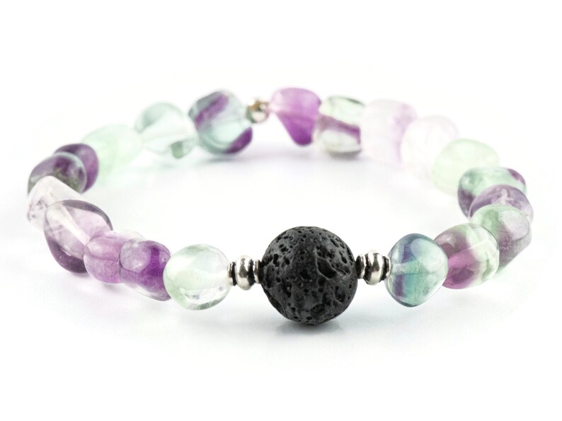 Puede incluir: Un brazalete hecho con piedras de fluorita verde, p&uacute;rpura y blanca y una cuenta de lava negra.
