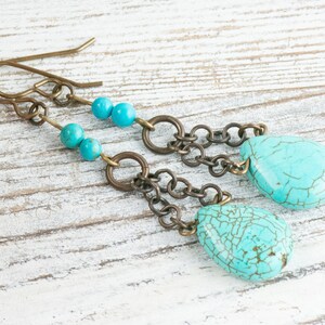 May include: Turquoise and brass dangle earrings with a teardrop shaped turquoise stone and small turquoise beads.
