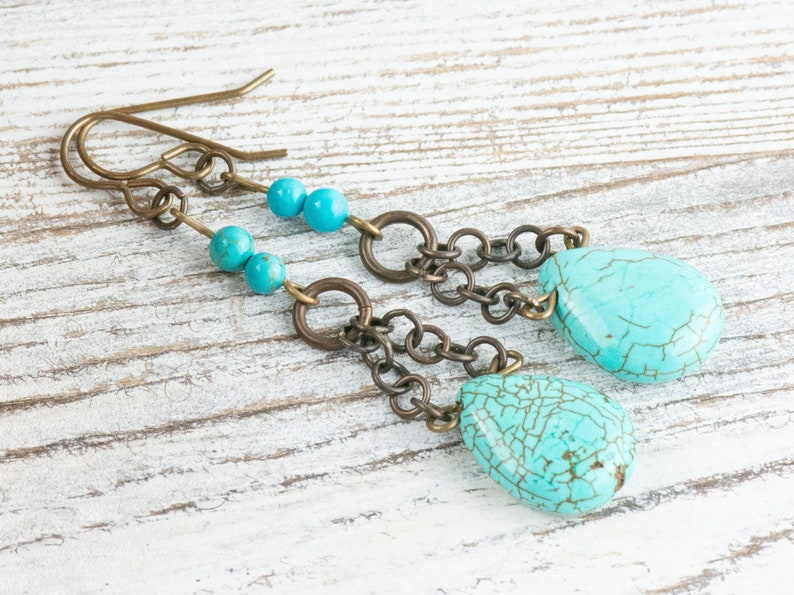 May include: Turquoise and brass dangle earrings with a teardrop shaped turquoise stone and small turquoise beads.