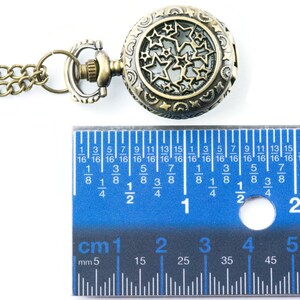 May include: A gold-toned pocket watch with a chain. The watch face has a cutout design of stars. The watch is 2.5 cm in diameter.