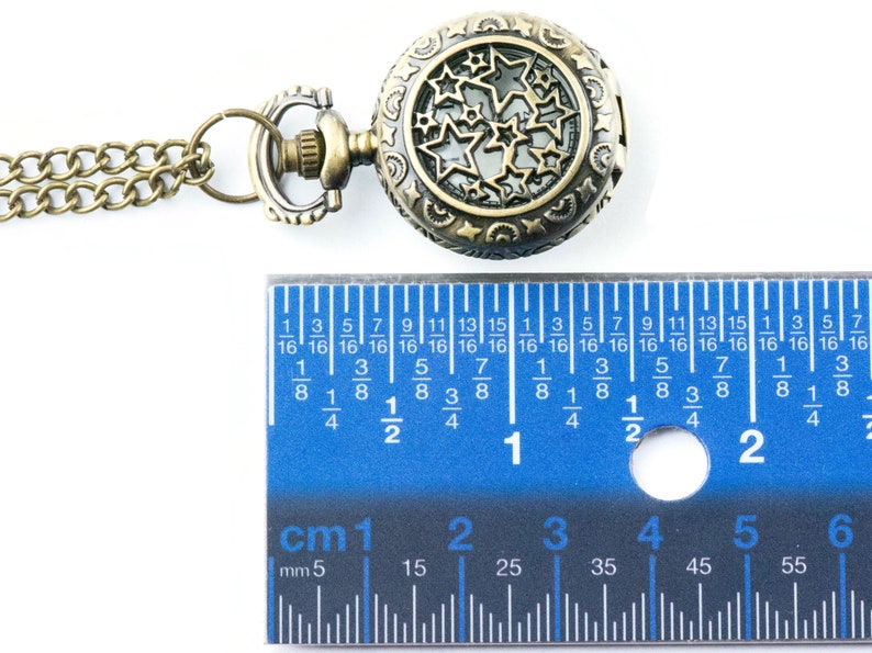 May include: A gold-toned pocket watch with a chain. The watch face has a cutout design of stars. The watch is 2.5 cm in diameter.