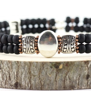 Button and Bows Jet Black Cuff Memory Wire Bracelet close up on a wood piece with tree bark edging