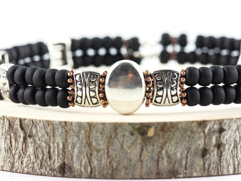 Button and Bows Jet Black Cuff Memory Wire Bracelet close up on a wood piece with tree bark edging