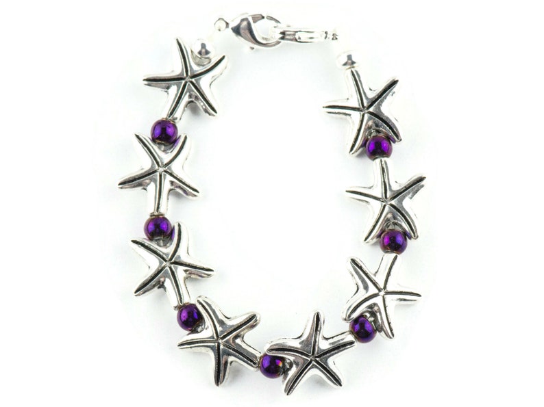 May include: A silver bracelet with a series of starfish charms and purple beads.