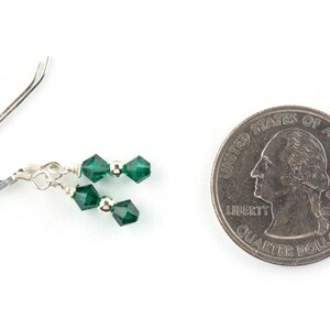 Peut inclure: Une paire de boucles d'oreilles pendantes en argent avec deux perles de cristal vert &eacute;meraude sur chaque boucle d'oreille. Les boucles d'oreilles sont pr&eacute;sent&eacute;es &agrave; c&ocirc;t&eacute; d'un quart de dollar am&eacute;ricain pour comparaison de taille.