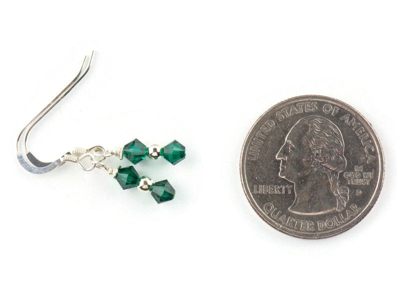 Peut inclure: Une paire de boucles d'oreilles pendantes en argent avec deux perles de cristal vert &eacute;meraude sur chaque boucle d'oreille. Les boucles d'oreilles sont pr&eacute;sent&eacute;es &agrave; c&ocirc;t&eacute; d'un quart de dollar am&eacute;ricain pour comparaison de taille.