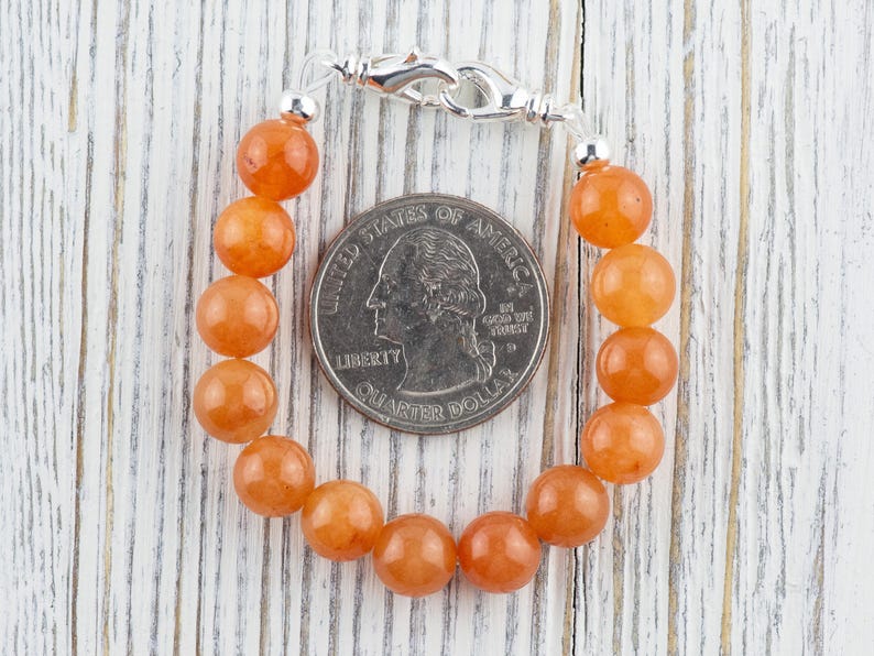 Op de afbeelding: Een armband gemaakt van oranje carneol kralen met een zilveren sluiting. De armband is ongeveer zo groot als een Amerikaanse kwart.
