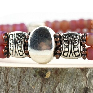 Button and Bows Raspberry Sorbet Cuff Memory Wire Bracelet close up on a wood piece with tree bark edging