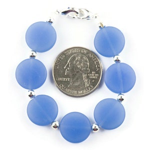 Peut inclure: Un bracelet de perles en verre bleu clair avec des perles argent&eacute;es et un fermoir argent&eacute;. Le bracelet est &agrave; peu pr&egrave;s de la taille d'une pi&egrave;ce de 25 cents am&eacute;ricaine.