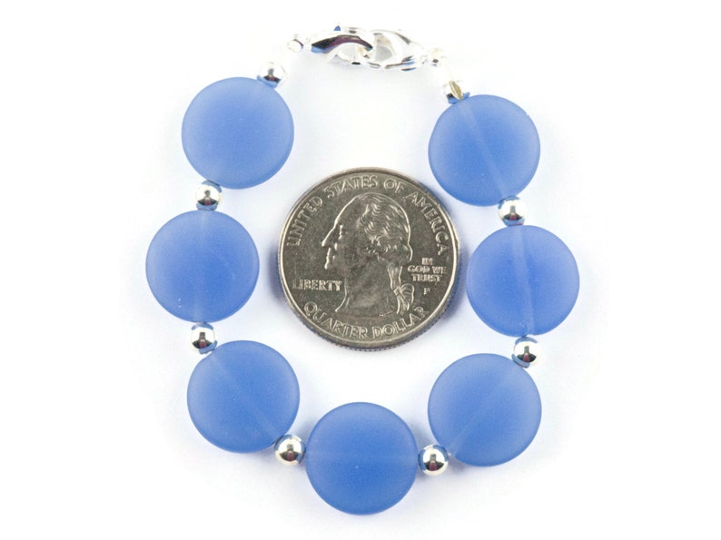 Peut inclure: Un bracelet de perles en verre bleu clair avec des perles argent&eacute;es et un fermoir argent&eacute;. Le bracelet est &agrave; peu pr&egrave;s de la taille d'une pi&egrave;ce de 25 cents am&eacute;ricaine.
