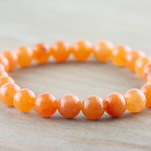 May include: A bracelet made of orange carnelian beads. The beads are round and smooth, and the bracelet is elastic.