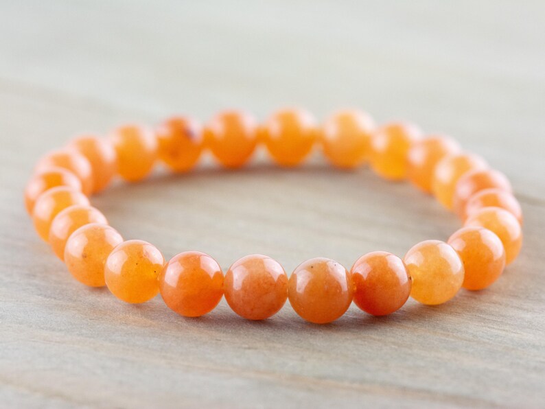 May include: A bracelet made of orange carnelian beads. The beads are round and smooth, and the bracelet is elastic.