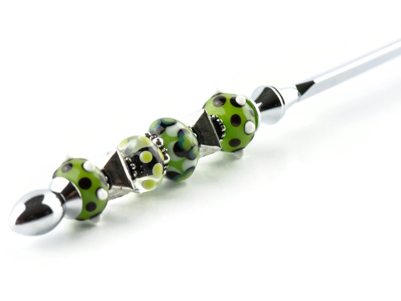 May include: A silver pen with a green and white patterned bead handle.