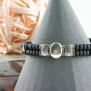 Button and Bows Jet Black Cuff Memory Wire Bracelet on a decorative black bracelet stand.